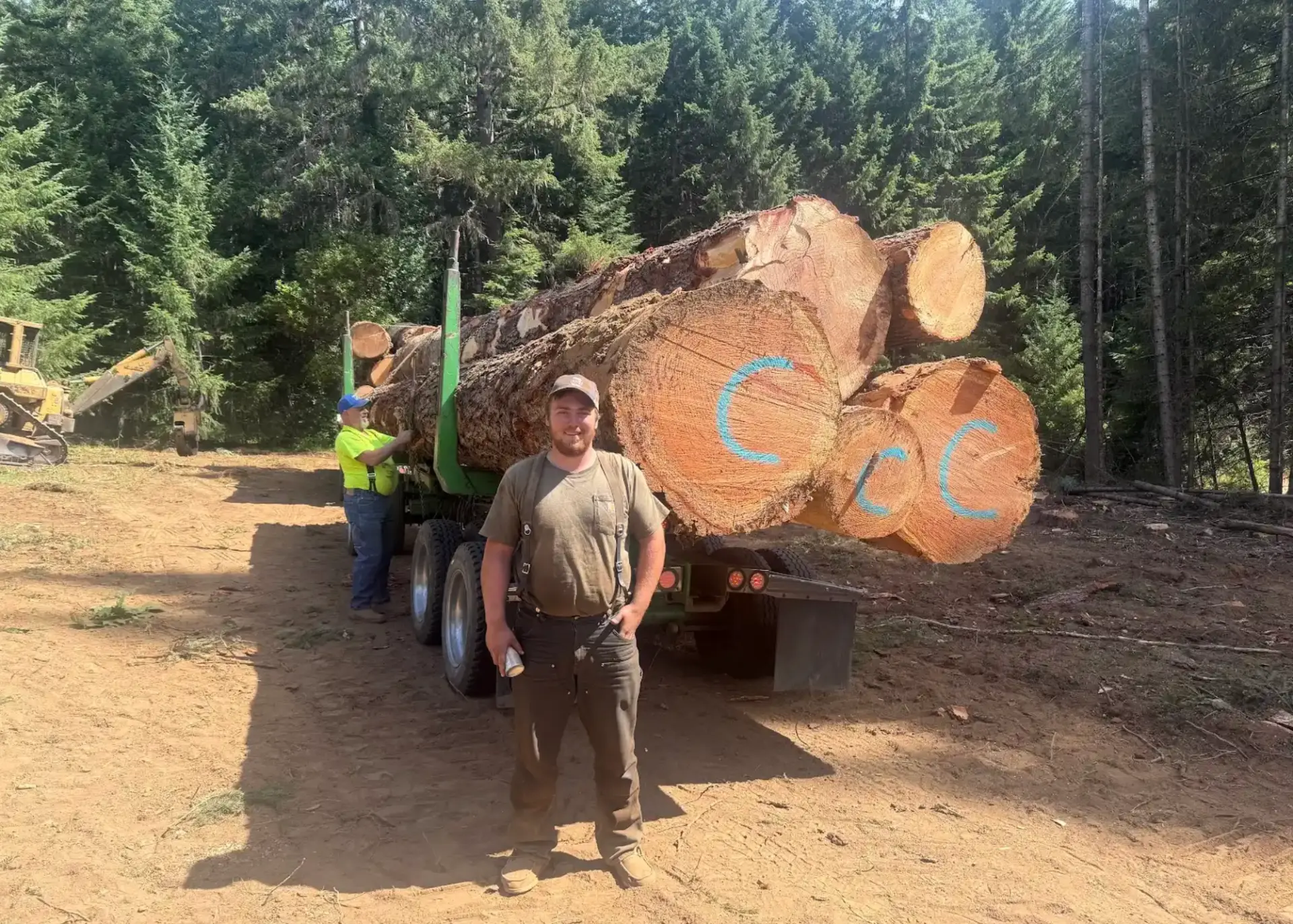 Father and son crew of Sweeney Logging and Timber beside a loaded log truck